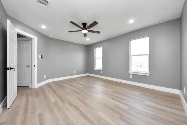 a view of empty room with wooden floor and fan