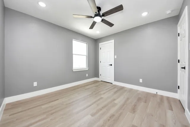 an empty room with windows and ceiling fan
