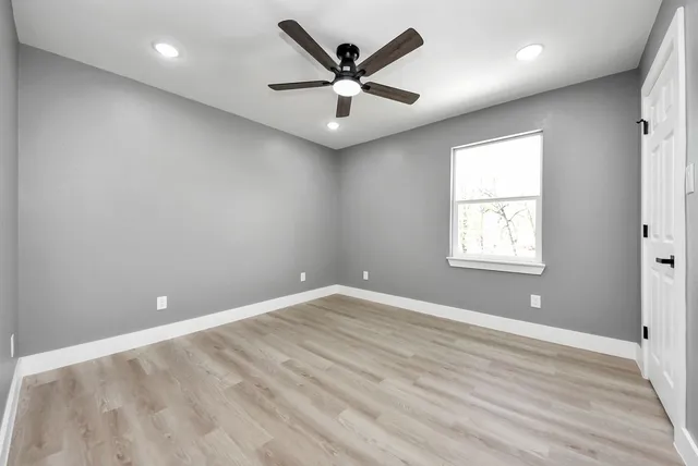 an empty room with windows and ceiling fan