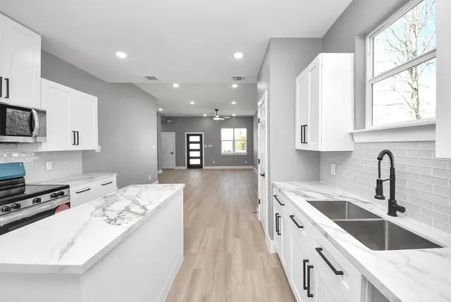 a kitchen with kitchen island granite countertop a sink appliances cabinets and a counter top space