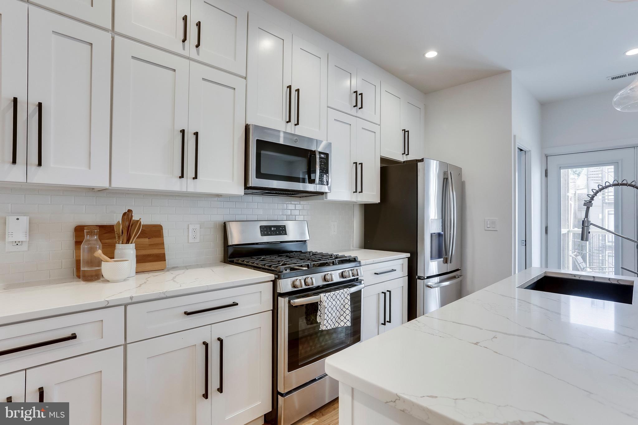 53 R Street Northeast, Unit 2 Washington, DC 20002 - Photo 5 of 25 a kitchen with granite countertop a refrigerator stove and microwave
