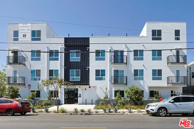a front view of a building with lot of cars and trees