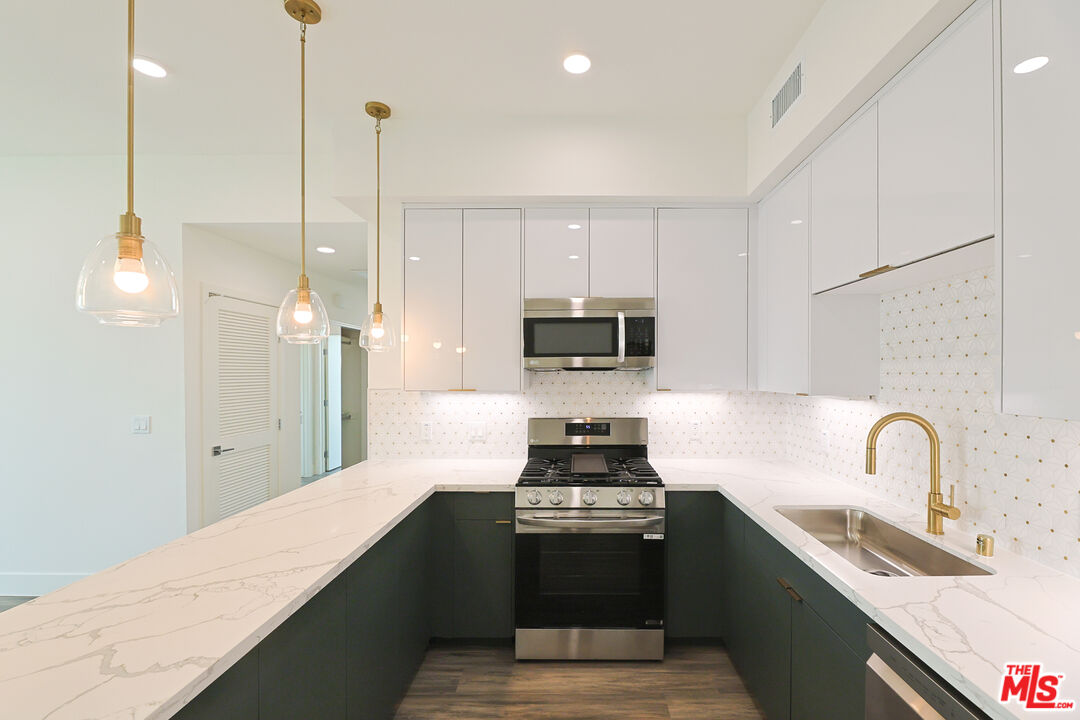 4000 Mont Clair Street, Unit 201 Los Angeles, CA 90018 - Photo 5 of 21 a kitchen with stainless steel appliances kitchen island a sink a stove and a refrigerator