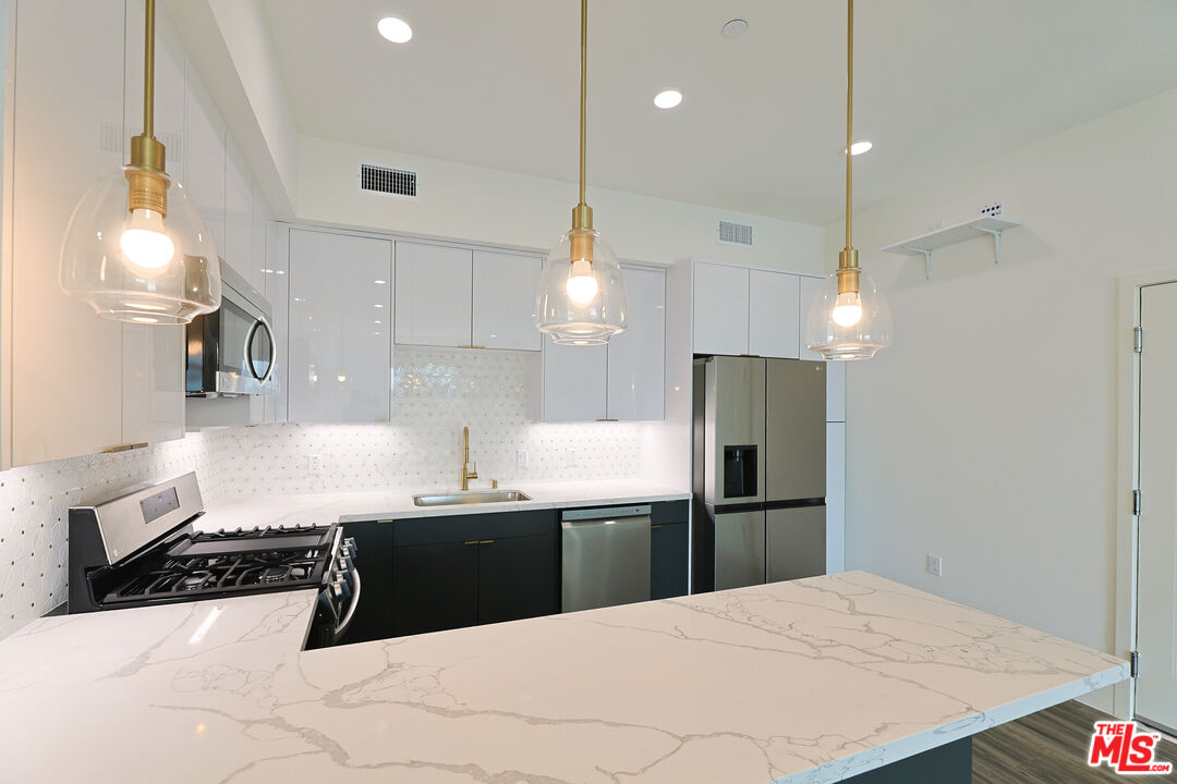 4000 Mont Clair Street, Unit 201 Los Angeles, CA 90018 - Photo 8 of 21 a kitchen with a sink a counter top space stainless steel appliances and cabinets