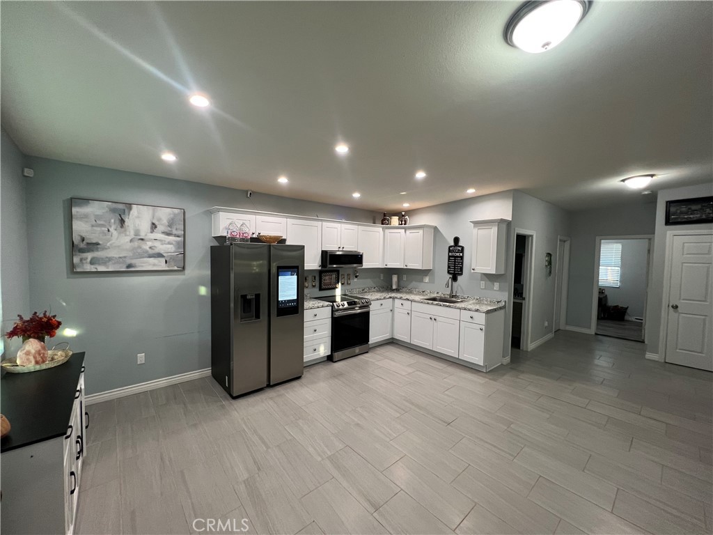 20240 Juniper Road Apple Valley, CA 92308 - Photo 3 of 25 a kitchen with stainless steel appliances kitchen island granite countertop a refrigerator and cabinets