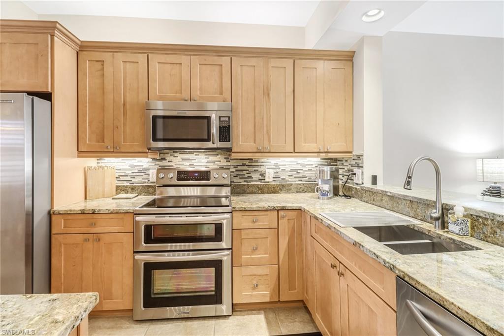 401 Bayfront Place, Unit 3205 Naples, FL 34102 - Photo 8 of 35 a kitchen with granite countertop white cabinets sink and stainless steel appliances