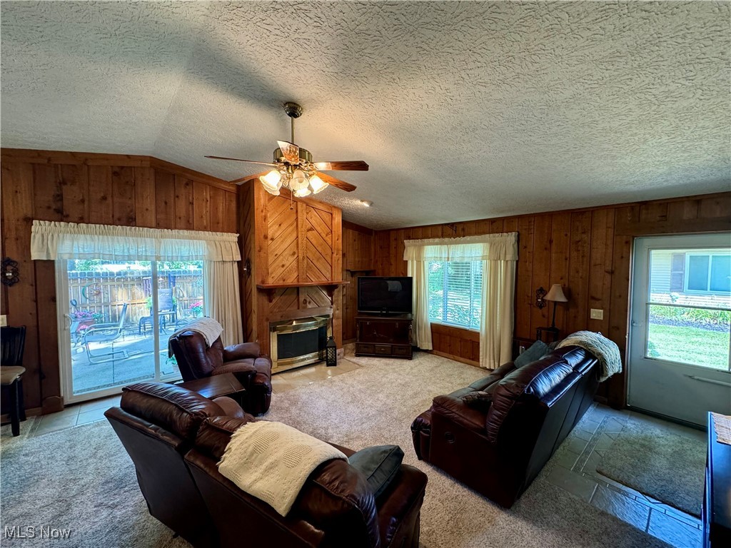 1499 Welch Road Painesville, OH 44077 - Photo 8 of 22 Living room with wood burning fireplace, natural light, ceiling fan, carpet floors, and lofted ceiling
