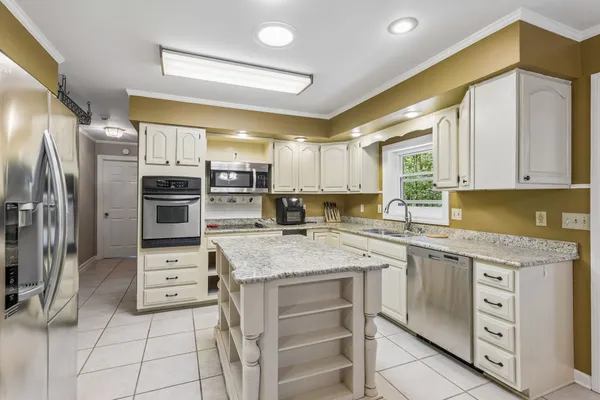 a kitchen with stainless steel appliances kitchen island granite countertop a sink stove and refrigerator