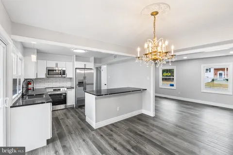 a kitchen with stainless steel appliances a stove top oven a refrigerator cabinets and wooden floor