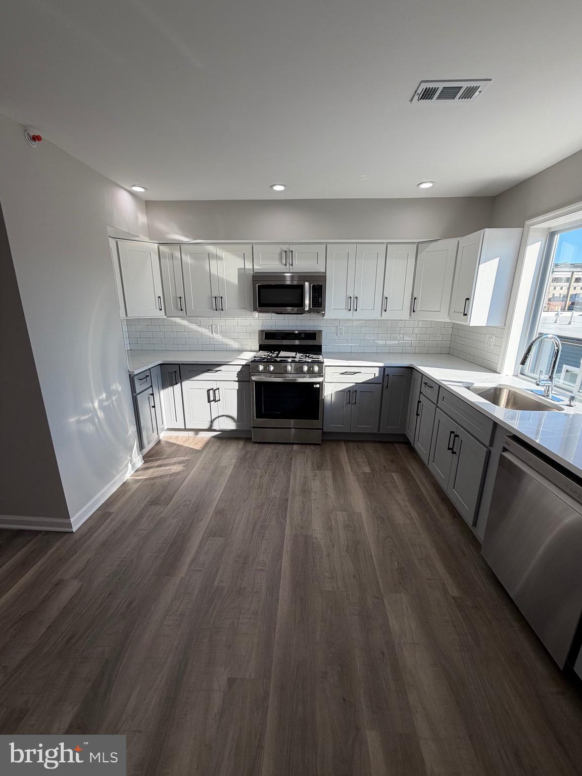 2218 Master Street Philadelphia, PA 19121 - Photo 48 of 66 a kitchen with granite countertop a stove top oven a sink dishwasher and white cabinets with wooden floor