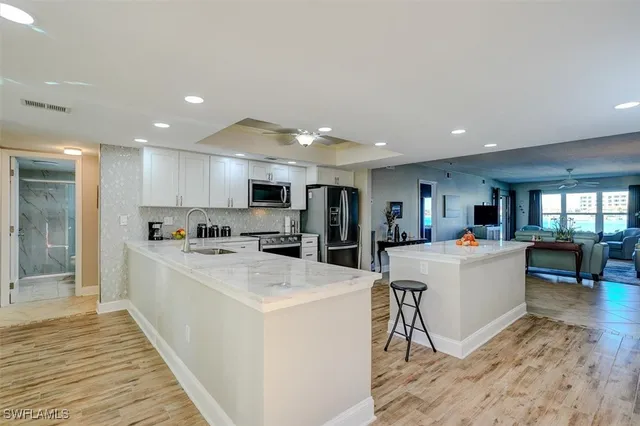 a large white kitchen with living room view