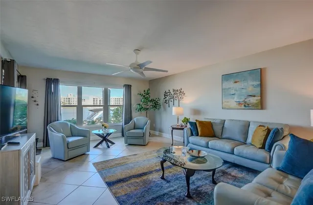 a living room with furniture flat screen tv and a large window