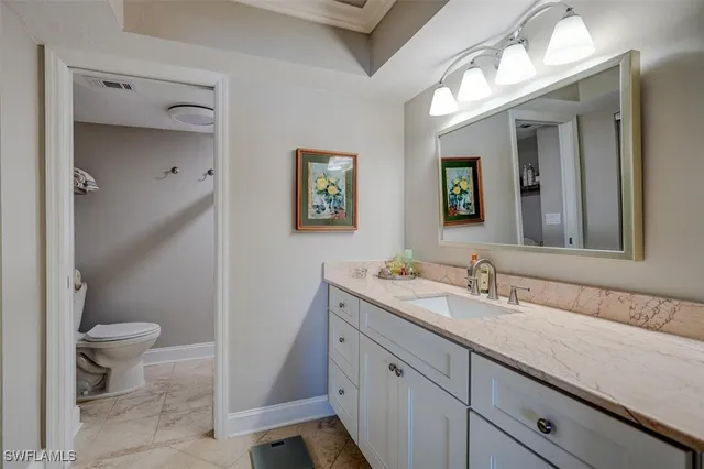 a bathroom with a granite countertop sink mirror vanity and toilet