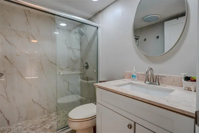 a bathroom with a granite countertop sink a toilet and a mirror