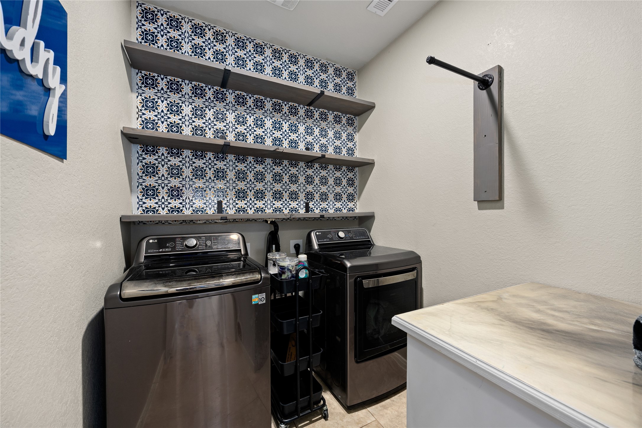 14023 Beaverhead Range Court Conroe, TX 77384 - Photo 20 of 29 Make laundry a pleasure in this beautifully designed and highly functional laundry room! A striking blue and white patterned tile backsplash creates a designer look and adds a pop of personality. Open gray shelving provides perfect storage and display space for all your laundry essentials.