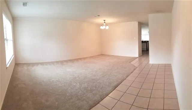 an empty room with kitchen view and window