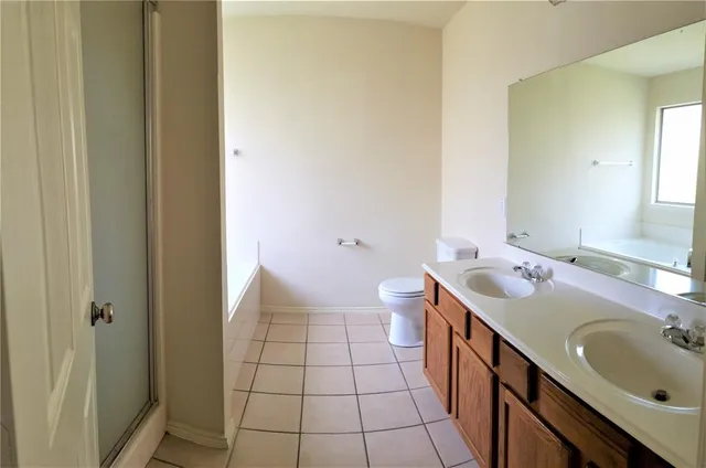 a spacious bathroom with a double vanity sink a toilet and a tub