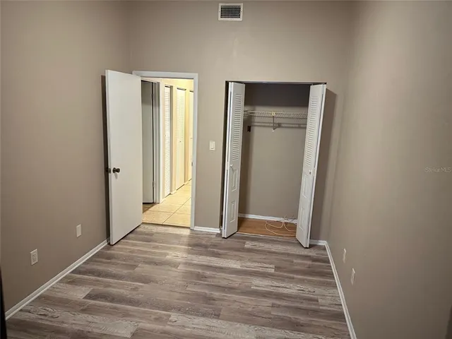 a view of a hallway with wooden floor and closet