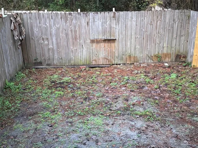a view of a house with a back yard and wooden fence