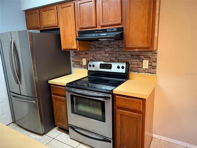 a kitchen with stainless steel appliances granite countertop a refrigerator and a stove top oven
