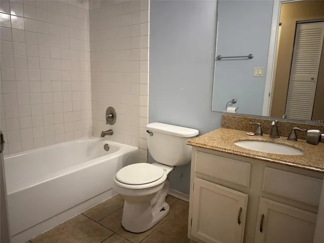 a bathroom with a granite countertop toilet a sink and a bathtub