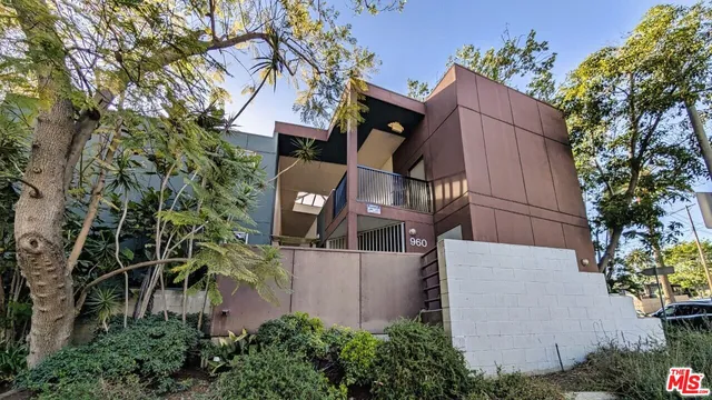a view of a wooden house with a tree and flower plants