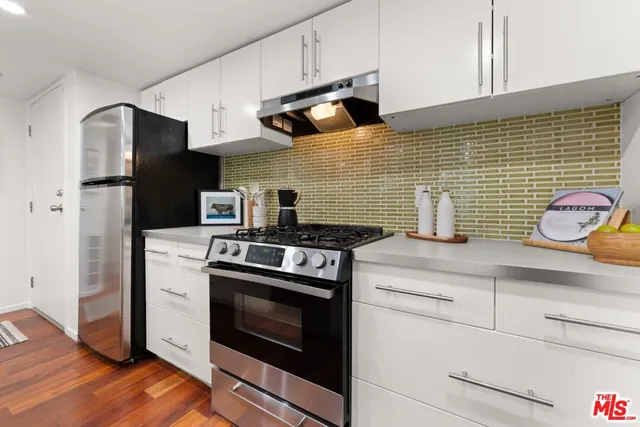 a kitchen with stainless steel appliances wooden floor sink and wooden cabinets