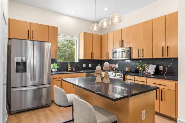 a kitchen with stainless steel appliances granite countertop a refrigerator a sink a stove and white cabinets