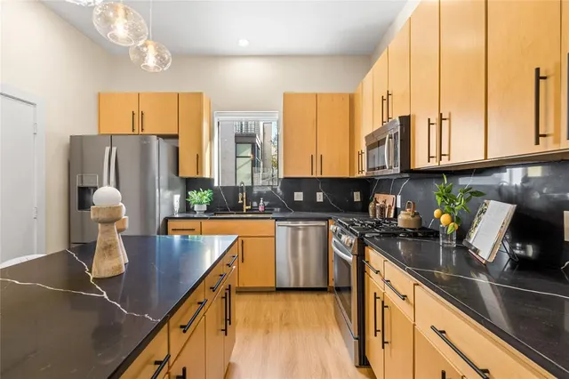 a kitchen with stainless steel appliances granite countertop a sink a stove and a refrigerator