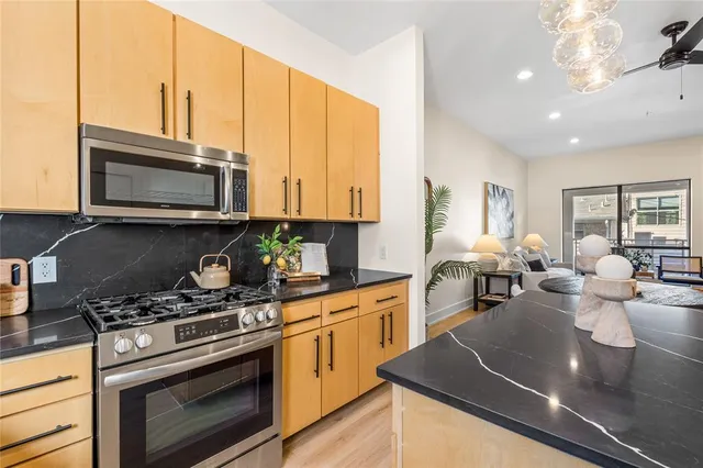 a kitchen with stainless steel appliances a stove a sink cabinets and a dining table