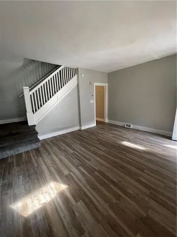 a view of an empty room with wooden floor and windows