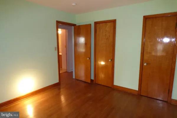 a view of an empty room with wooden floor and windows