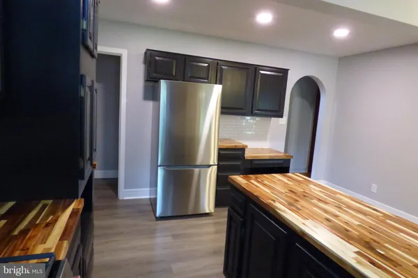a kitchen with kitchen island a counter top space a refrigerator and wooden floor