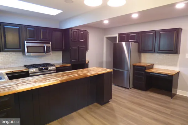 a kitchen with stainless steel appliances granite countertop a refrigerator a stove top oven and a sink
