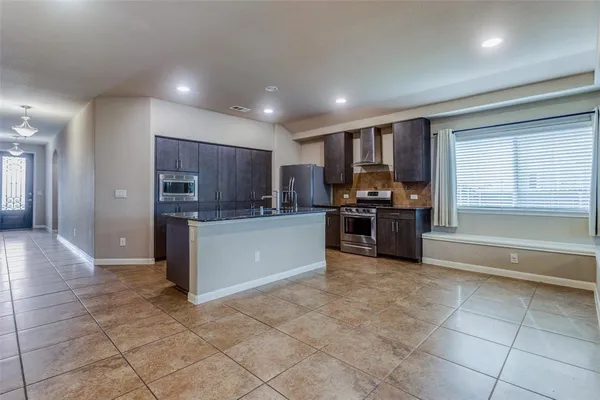 a kitchen with stainless steel appliances granite countertop a refrigerator and a stove top oven