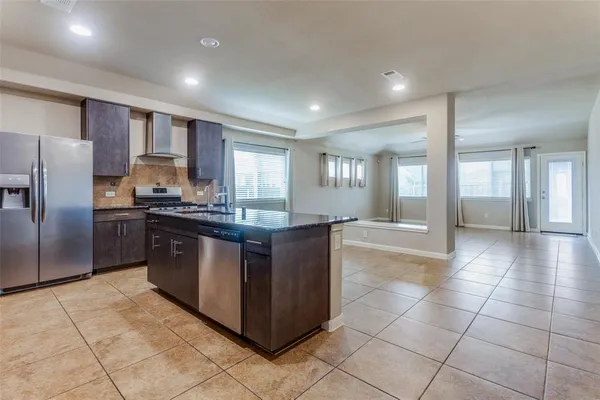 a kitchen with stainless steel appliances granite countertop a stove a sink a refrigerator a counter top space and cabinets