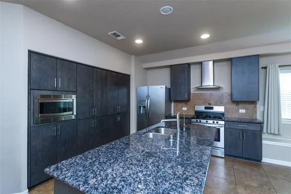 a kitchen with stainless steel appliances kitchen island granite countertop a refrigerator stove and sink