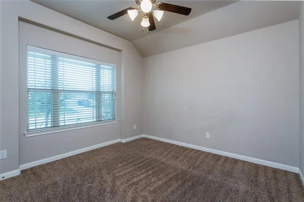 an empty room with a chandelier fan and windows