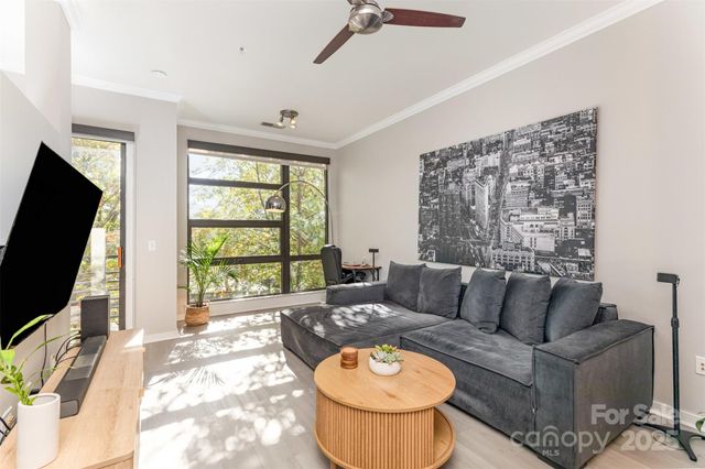 a living room with furniture a flat screen tv and a large window
