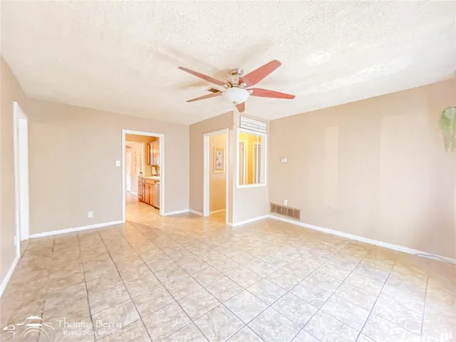 an empty room with windows and fan