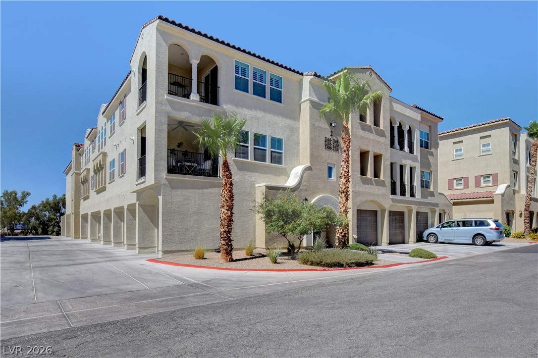 2555 Hampton Road, Unit 2207 Henderson, NV 89052 - Photo 73 of 74 Mediterranean-inspired multi-story residence boasts architectural arches and private balconies, complemented by palm tree landscaping.