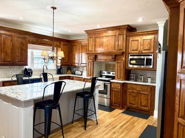 4310 Enoch Road Aynor, SC 29511 - Photo 13 of 39 Kitchen with a kitchen bar, brown cabinetry, pendant lighting, decorative backsplash, and stainless steel appliances
