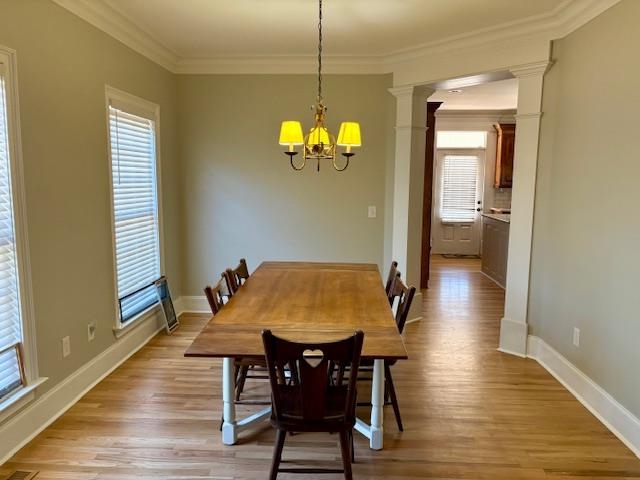 4310 Enoch Road Aynor, SC 29511 - Photo 7 of 39 Dining room featuring crown molding, light wood finished floors, decorative columns, and a chandelier
