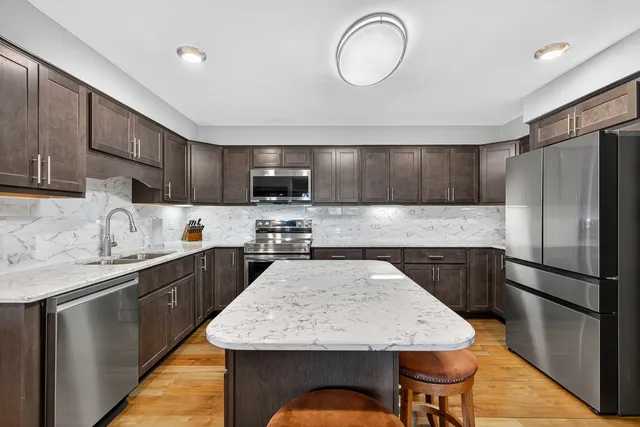 a kitchen with stainless steel appliances granite countertop a sink refrigerator stove and microwave