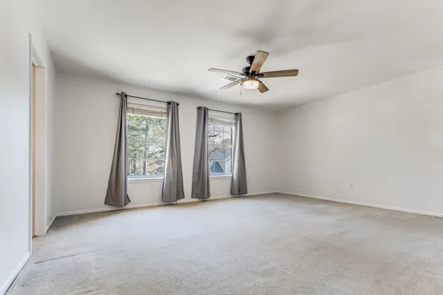 a view of a big room with windows and chandelier fan