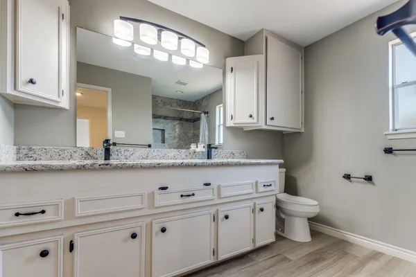 a bathroom with a granite countertop sink and a toilet