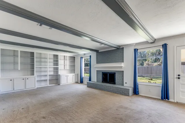 a view of an empty room with a fireplace and a window