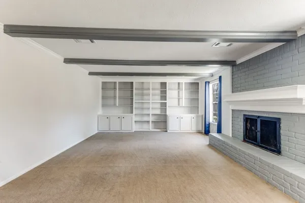 a view of an empty room with a fireplace and a window
