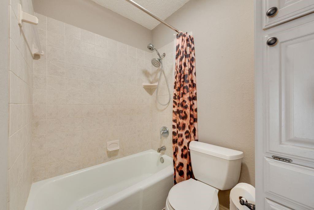 83 Crown Road Willow Park, TX 76087 - Photo 11 of 35 Tub and shower combination with tiled surround, showerhead, and built-in storage