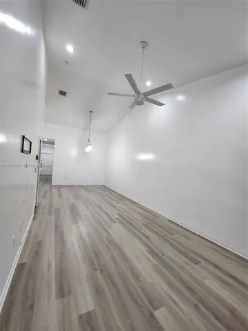 an empty room with wooden floor fan and windows